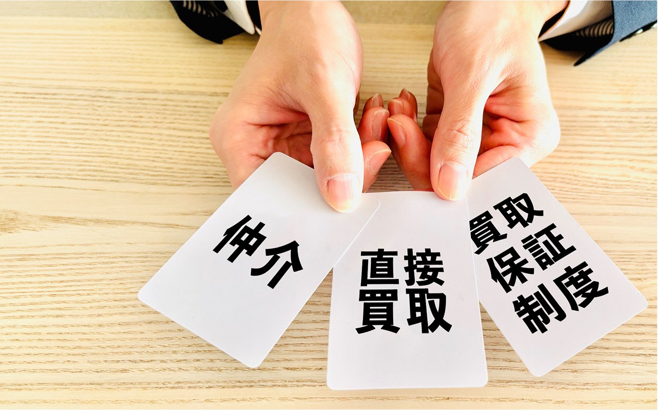 仲介・直接買取・買取保証制度の3枚のカードを差し出す手元